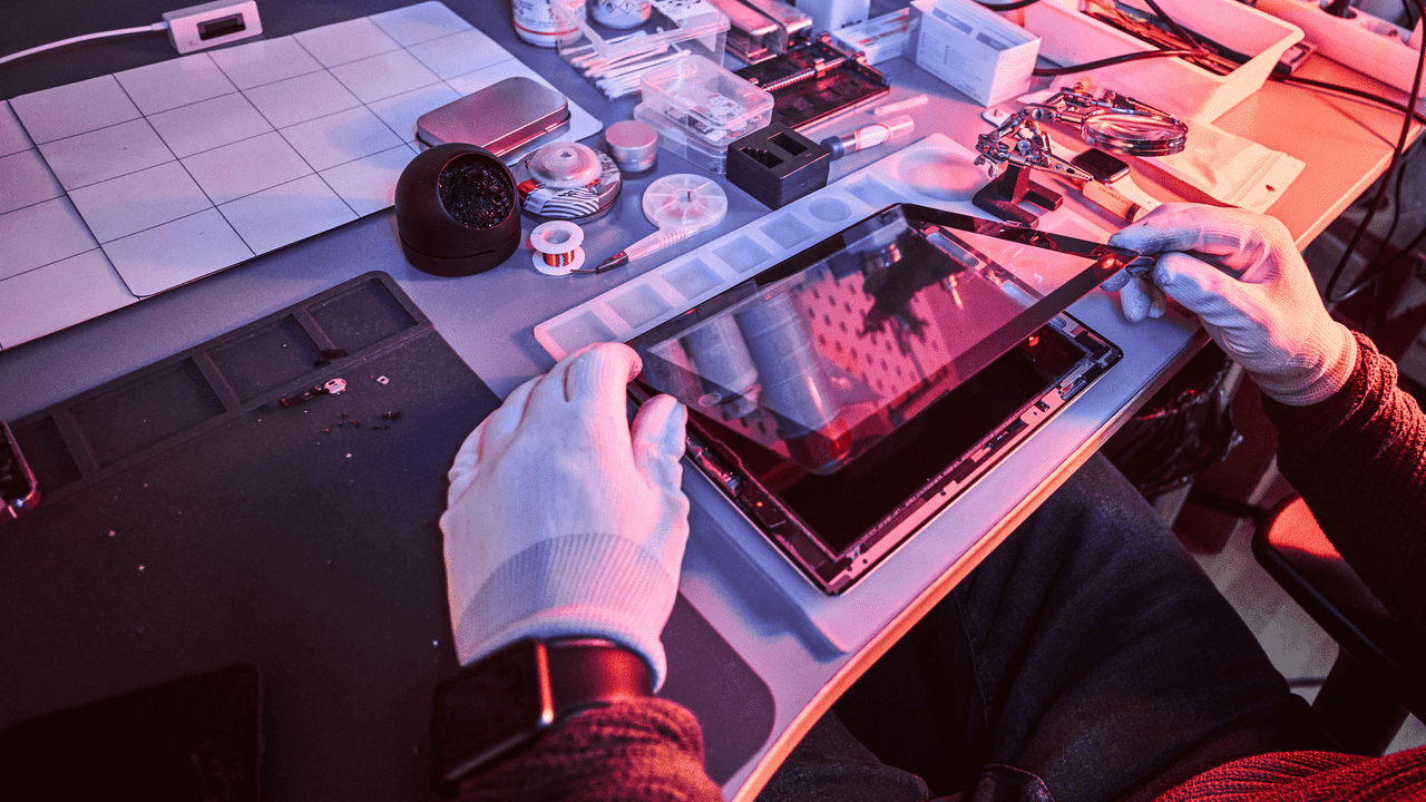 Mann repariert konzentriert iPad im Reparatur-Haus Augsburg – professionelle, sorgfältige Arbeit.